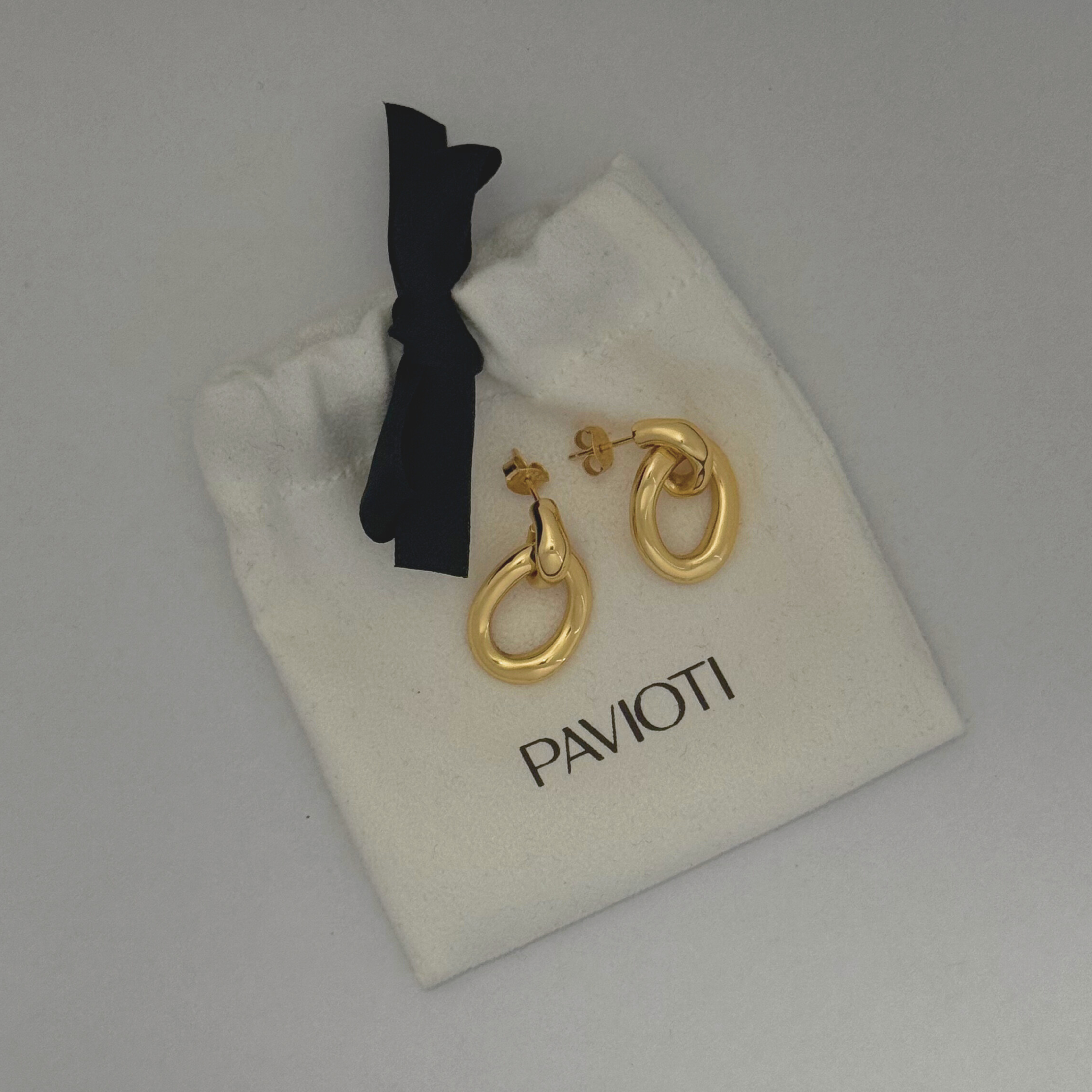 Gold earrings on a Pavioti branded jewelry pouch with a black bow.